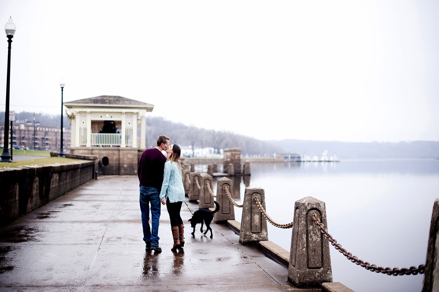 a couple with their dog, kissing by the river