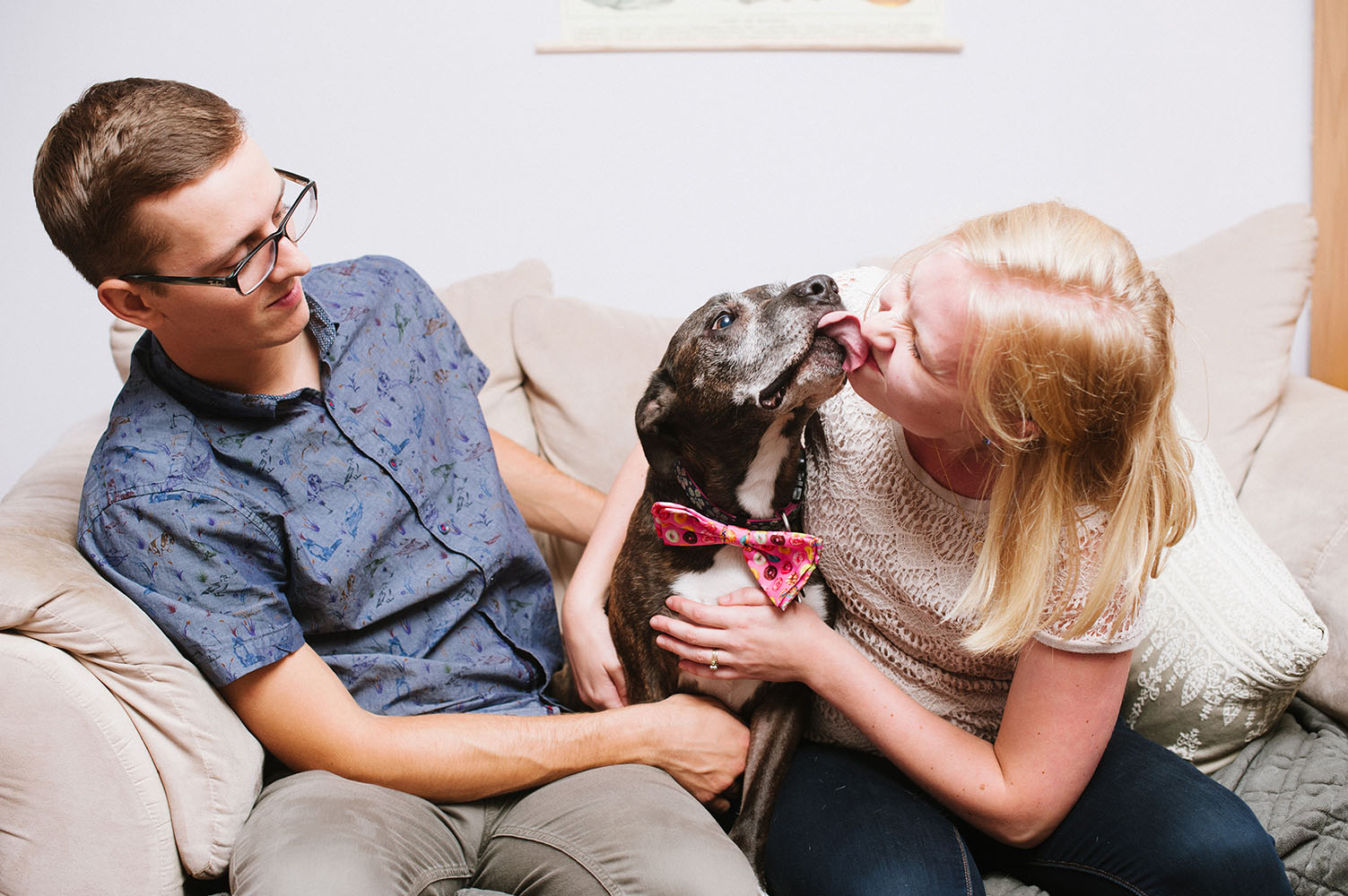 Young couple with dog licking girl