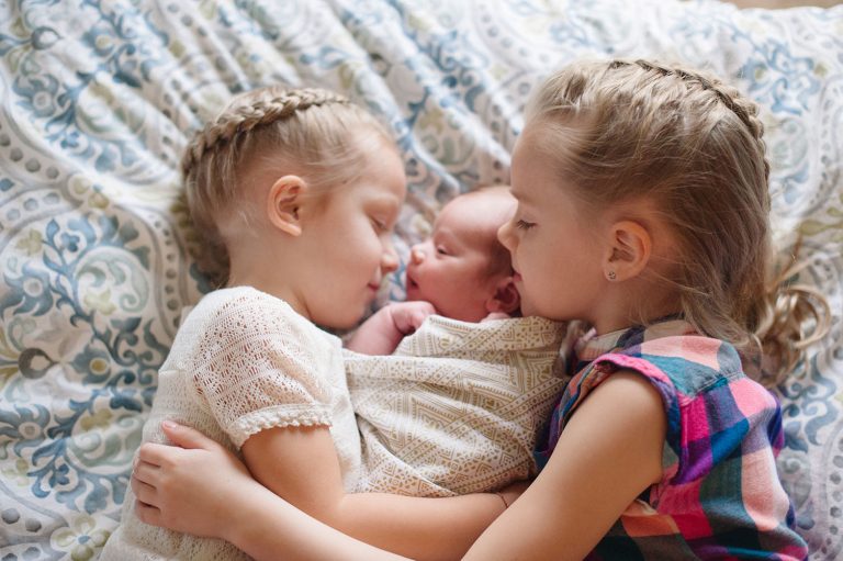 3 little girls snuggling on a bed