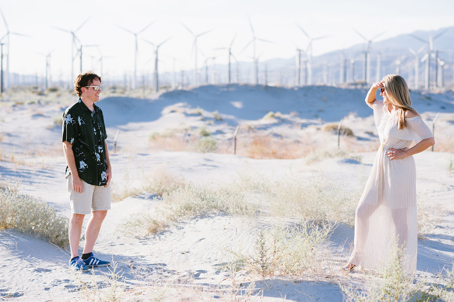 engaged couple in front of wind turbines in California