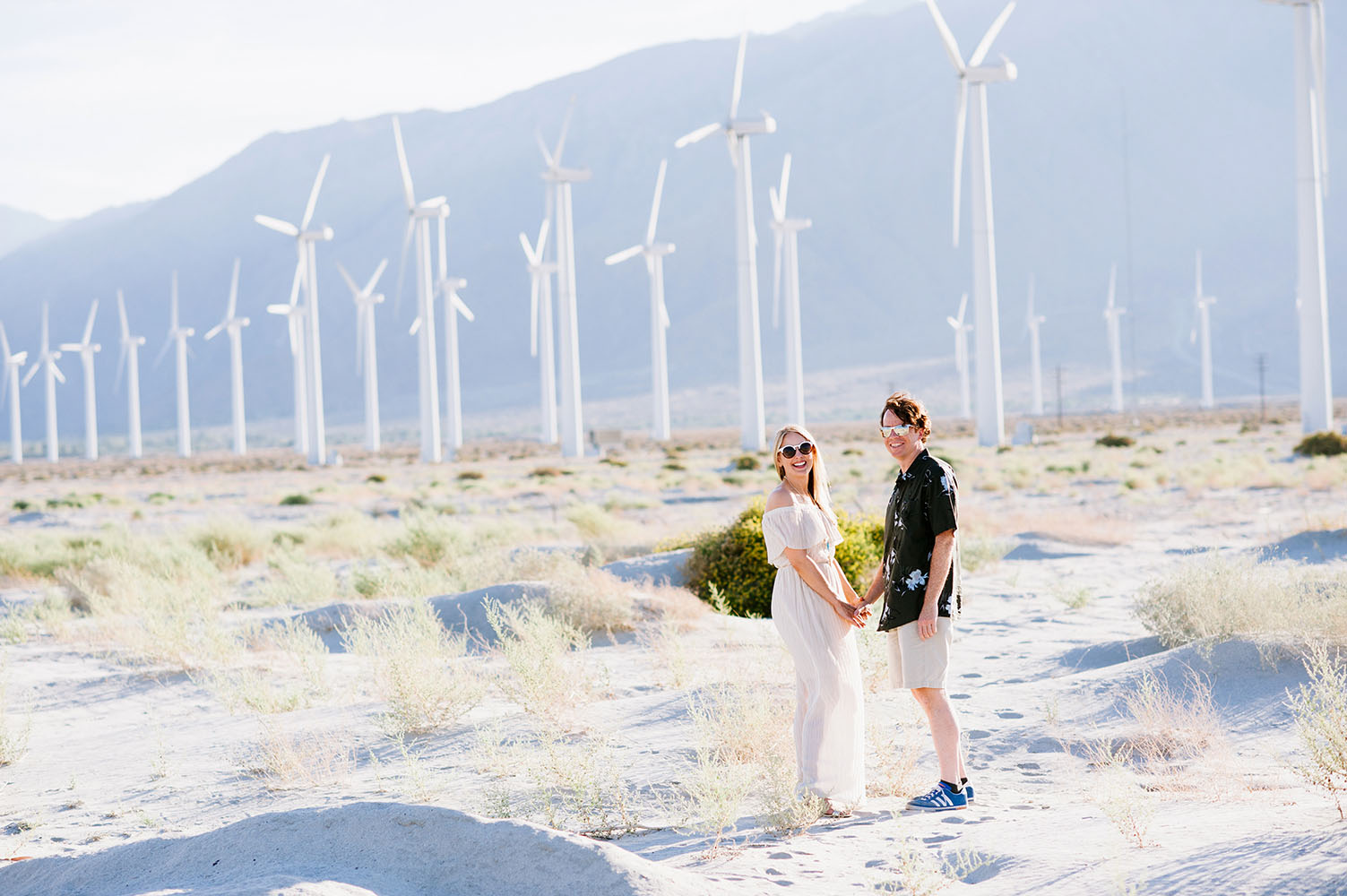 engaged couple in front of wind turbines in California