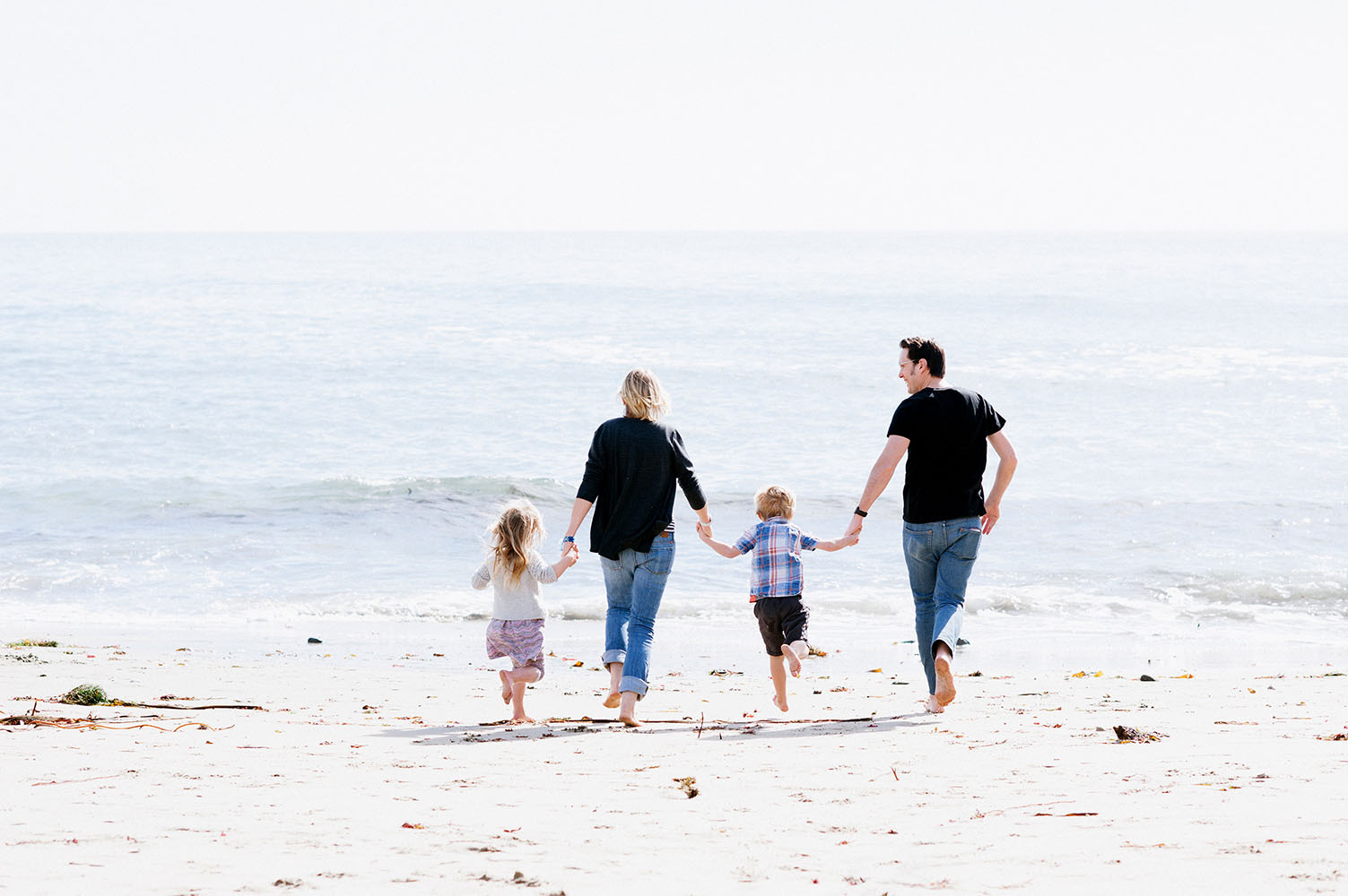 Family running towards ocean