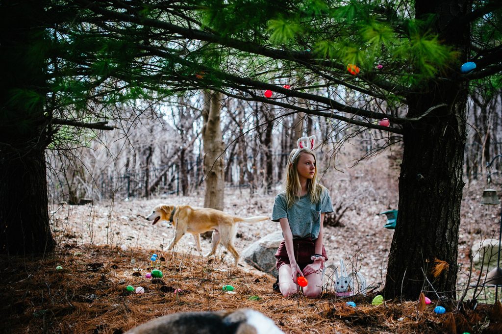 Girl hiding plastic eggs with bunny ears on