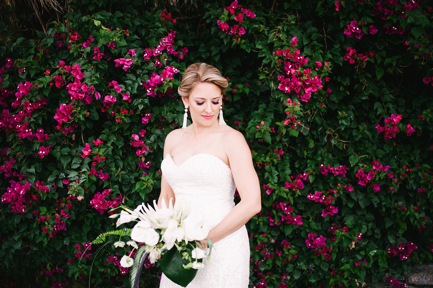 Bride in front of bougainvillea with protea bouquet a WToo dress