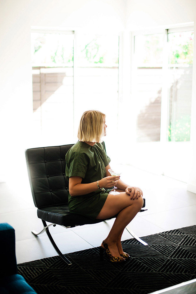 woman in green jumper with martini on Mies Van Der Rohe chair