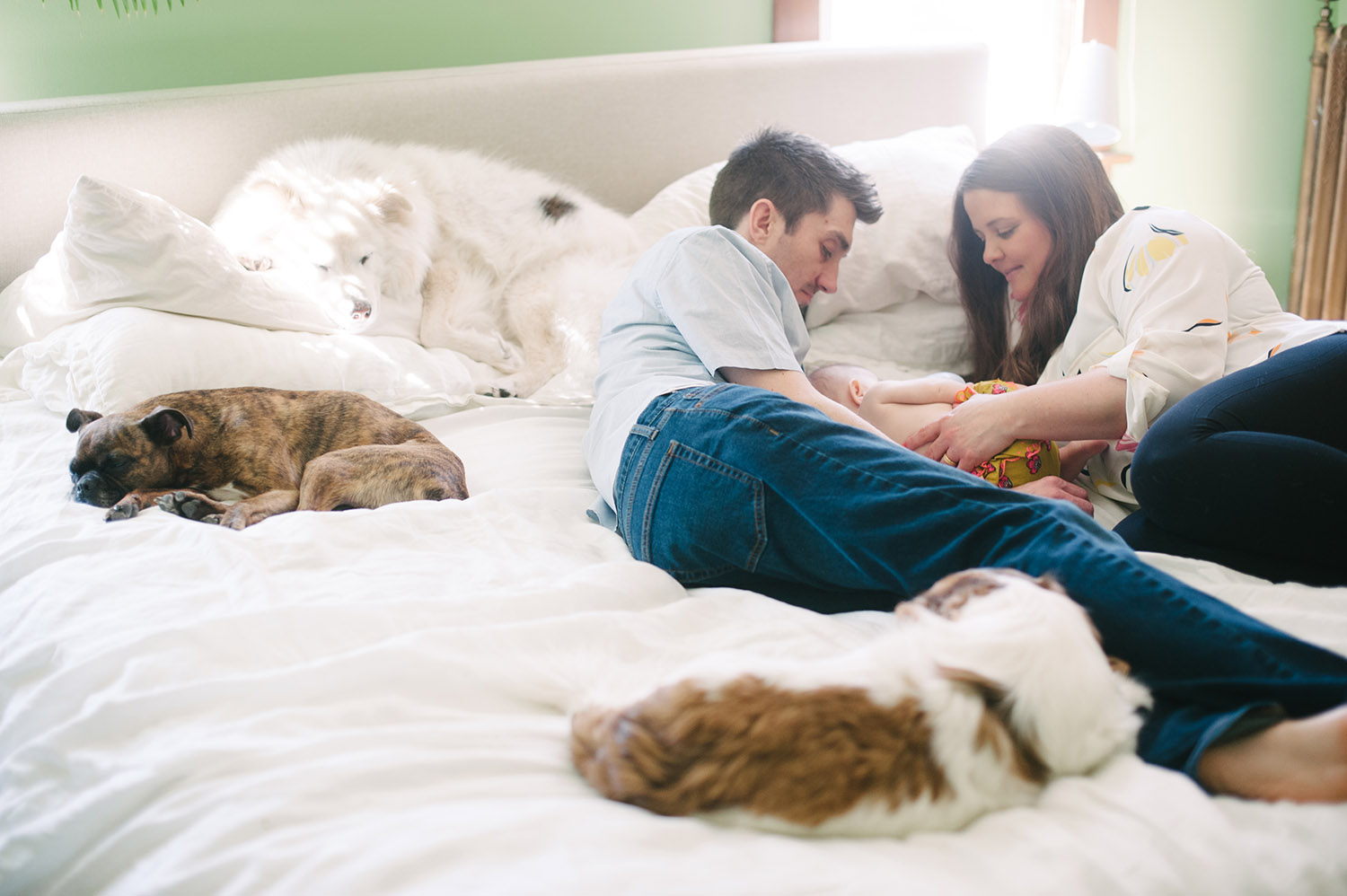 a couple on their bed with a baby and their dogs