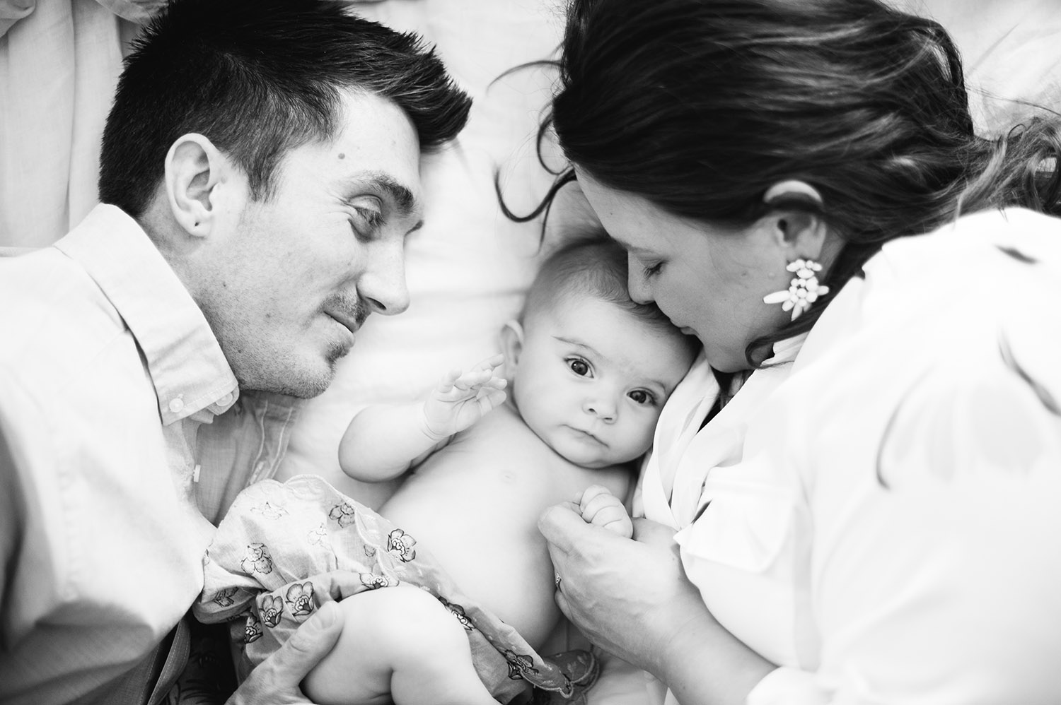 black and white photo of couple cuddling with their baby