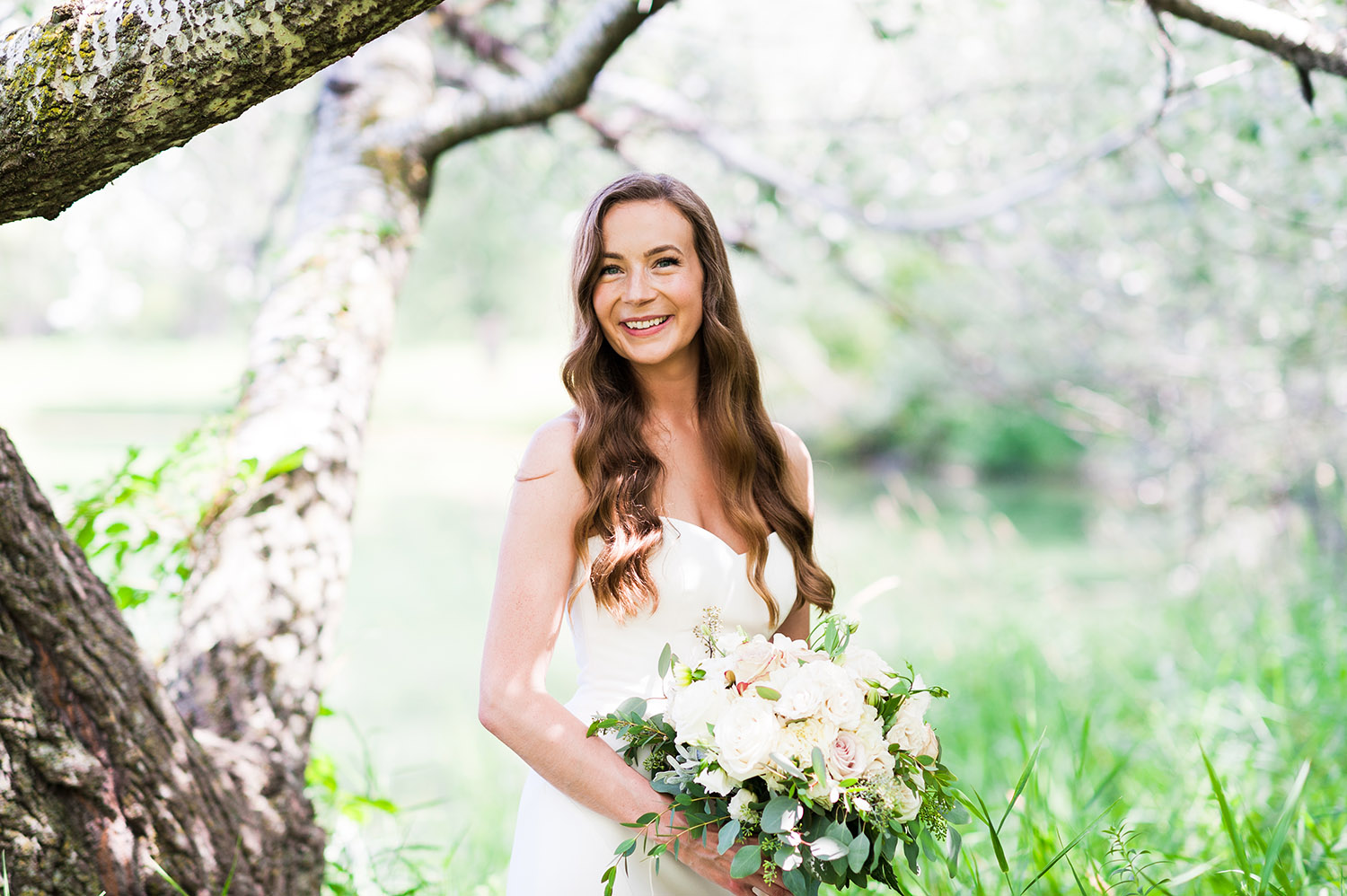 bride with long, dark wavy hair in nature with bouquet