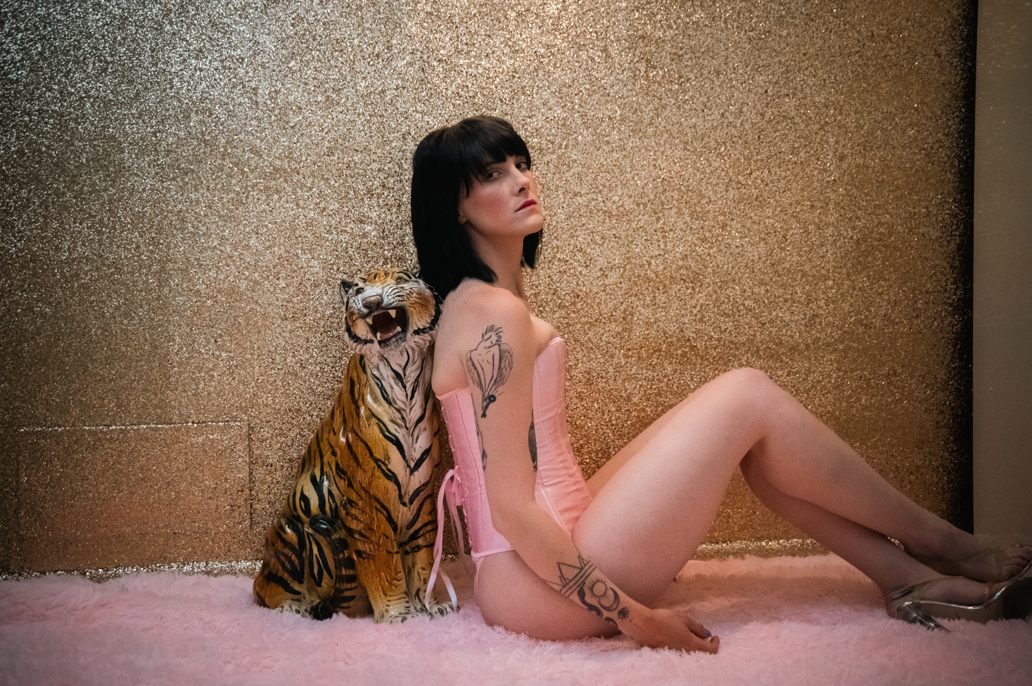 a white woman in pink lingerie next to a ceramic tiger at the Zebra House