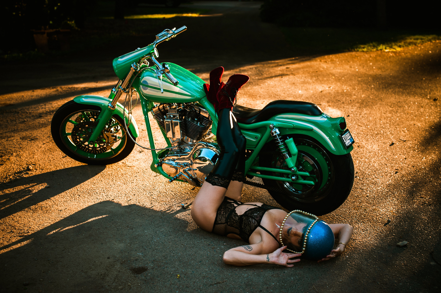 a white woman lying on the ground with her legs up on a green motorcycle at The Zebra House