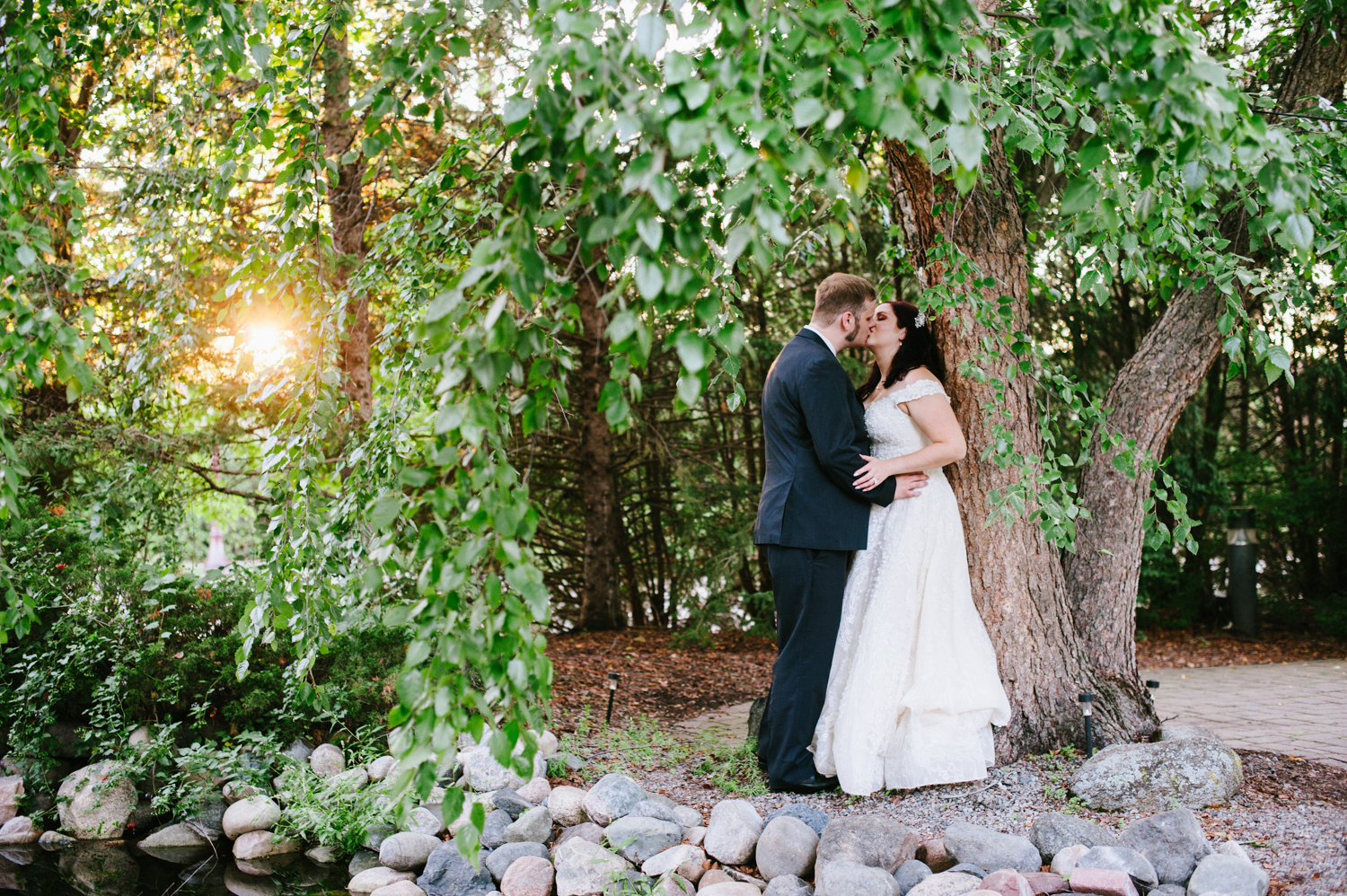 a married couple kissing under a tree