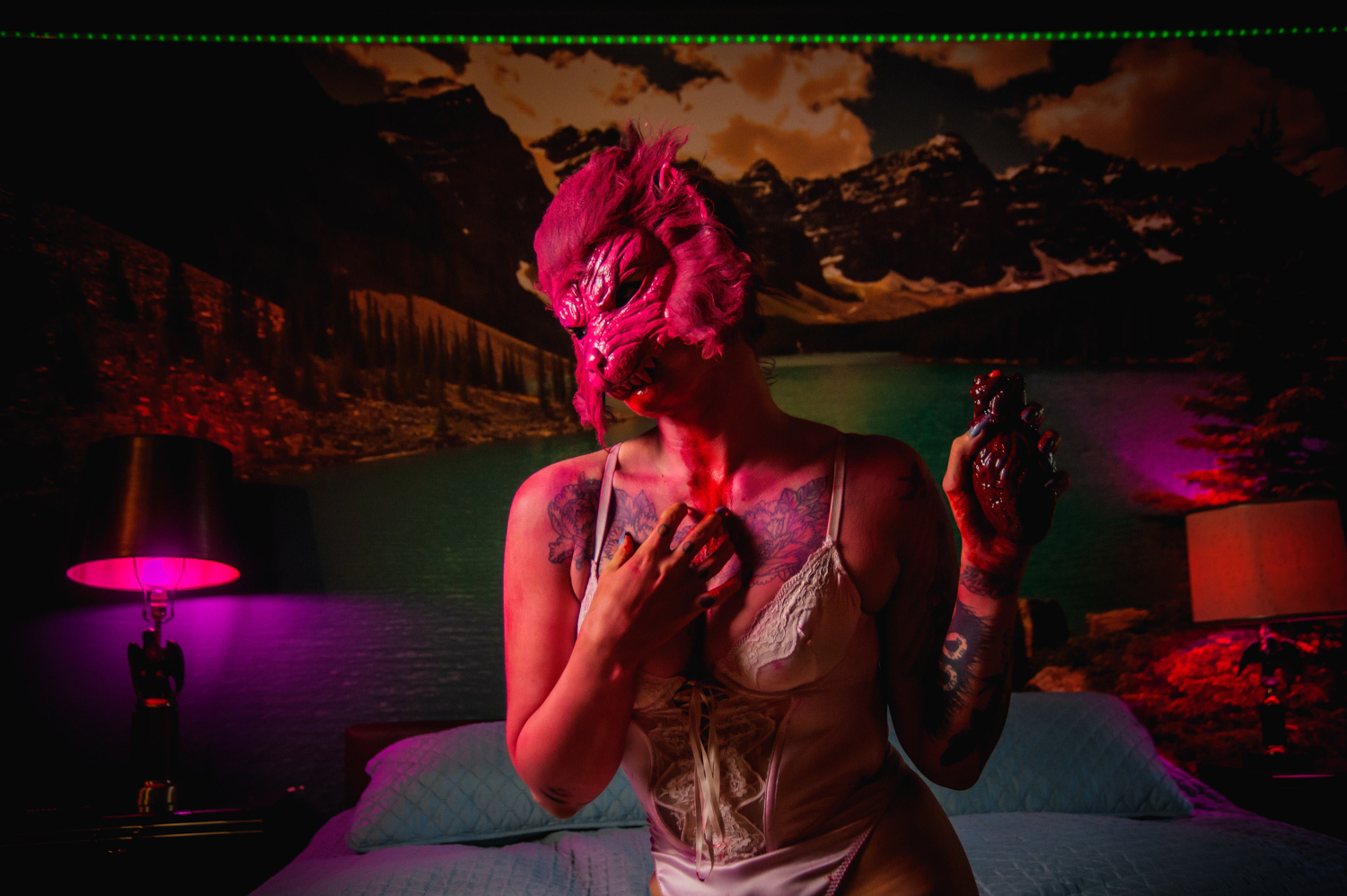 a woman holding a fake heart wearing a pink wolf mask in lingerie at Grandpas pool house