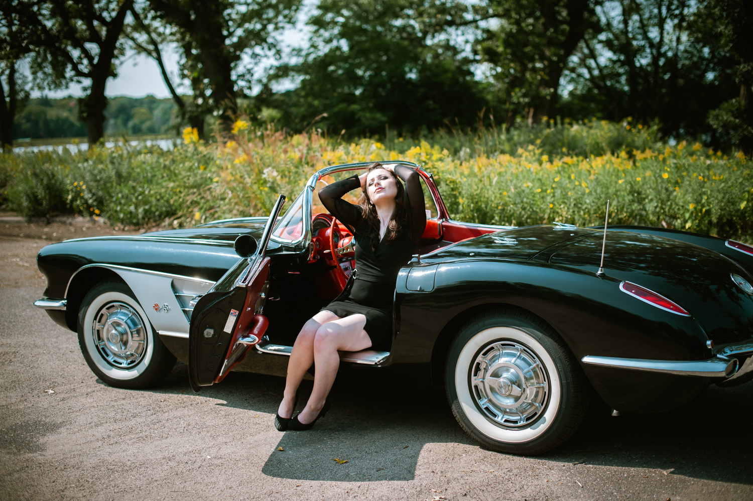 a beautiful woman sitting in a vintage black car boudoir