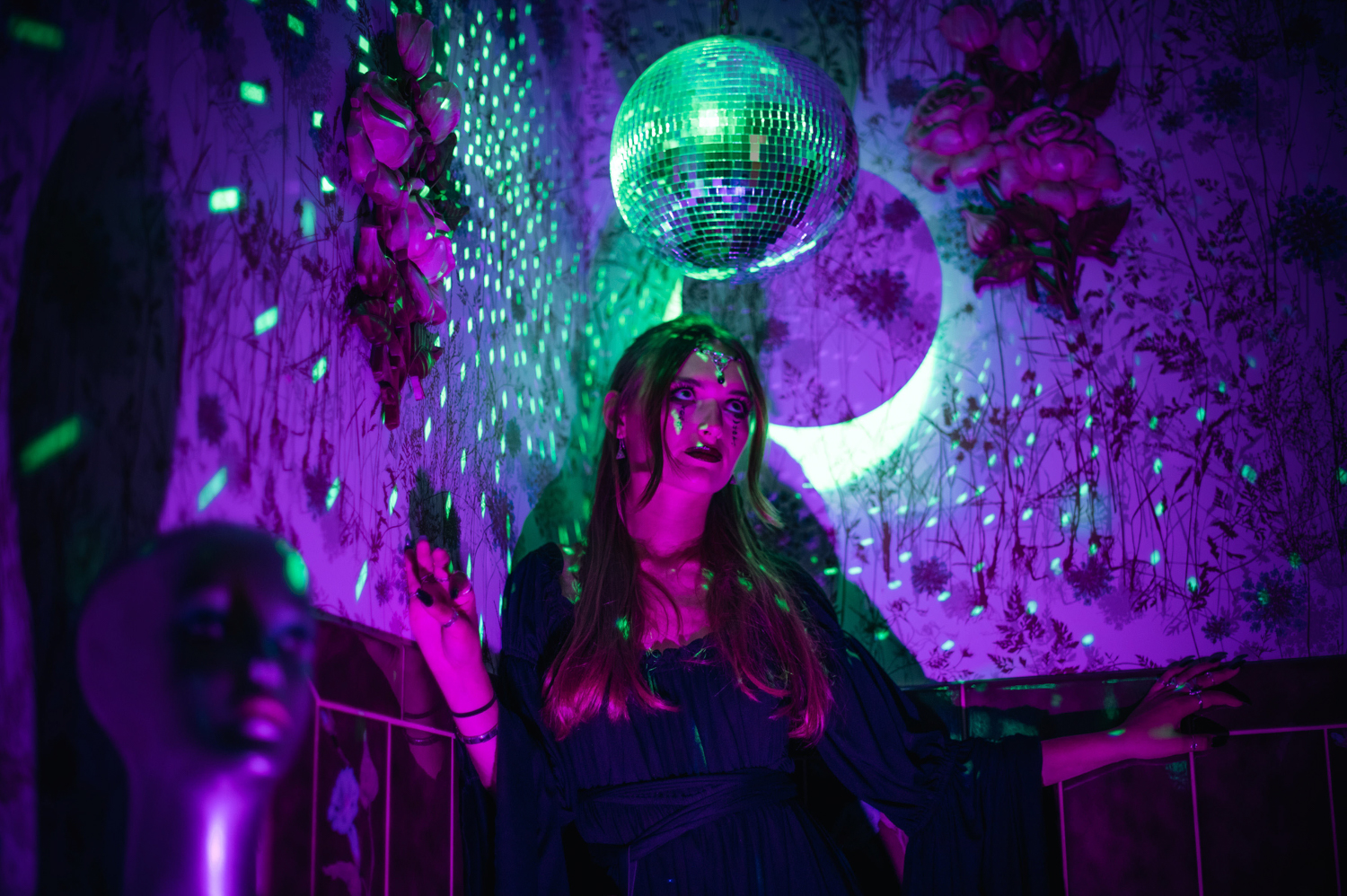 a witchy girl under a disco ball with purple lights at Grandpas pool house